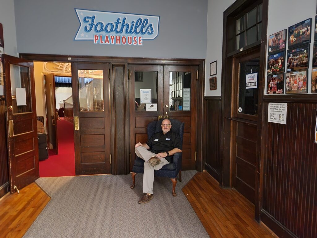 derick a pindroh sits in front of entrance to foothills playhouse easley sc